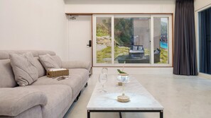 Een moderne woonkamer met een bank, een salontafel en uitzicht op een zwembad door grote glazen deuren.
