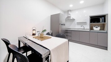 Una cocina moderna con microondas integrado, campana extractora de acero inoxidable y encimera con fregadero.