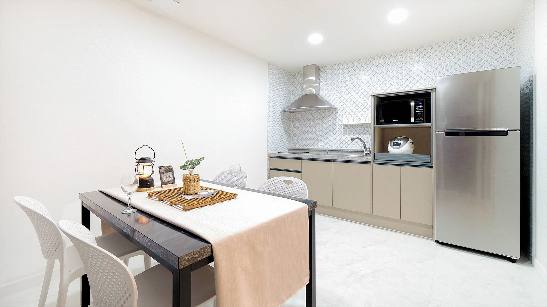 Une cuisine moderne équipée d’un réfrigérateur en acier inoxydable, d’une table à manger avec des chaises et d’un îlot de cuisine.