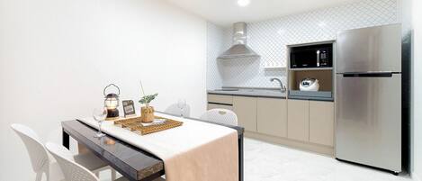Une cuisine moderne équipée d’un réfrigérateur en acier inoxydable, d’une table à manger avec des chaises et d’un îlot de cuisine.