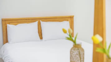 A bed with a wooden headboard and white bedding.