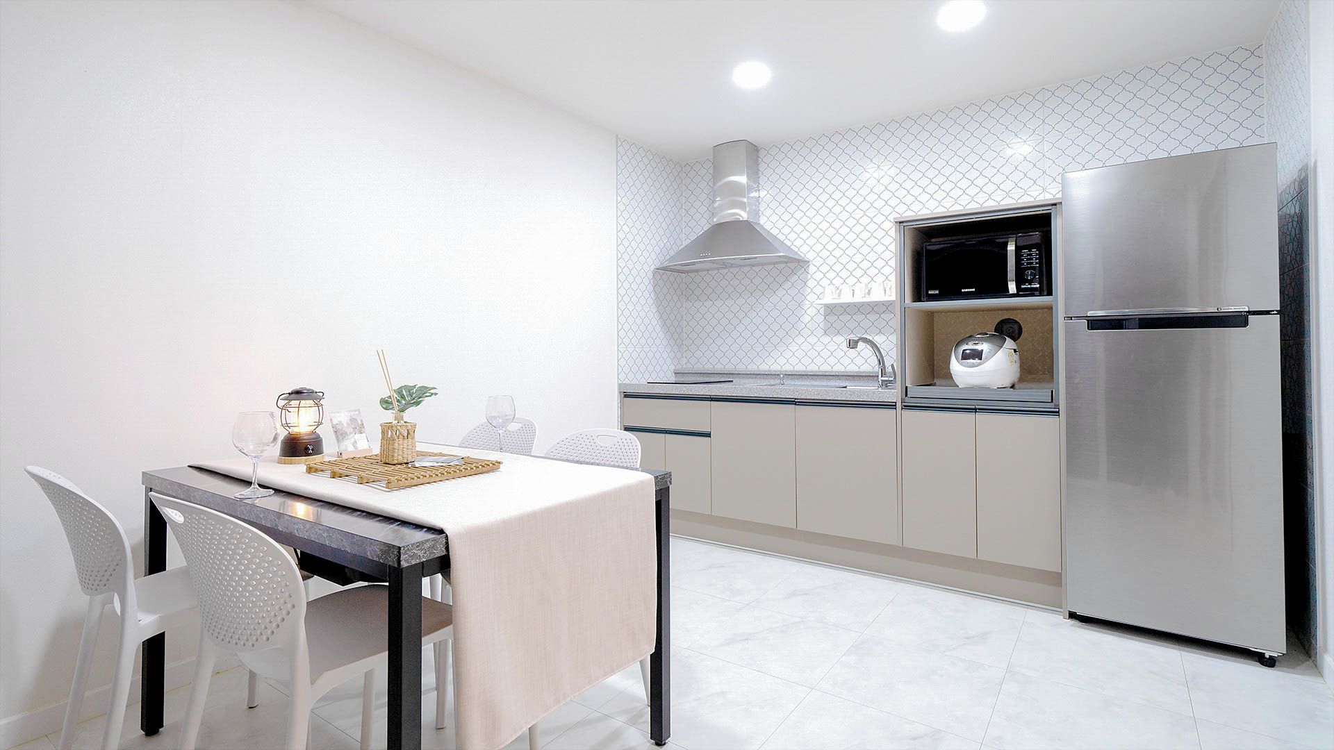 Una cucina moderna con zona pranzo, completa di frigorifero in acciaio inossidabile, microonde e piano cottura a gas.