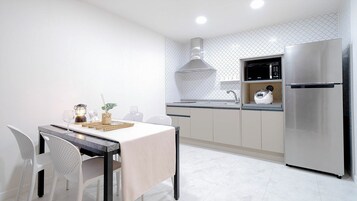 A modern kitchen with a dining area, featuring a stainless steel refrigerator, a microwave, and a gas range.