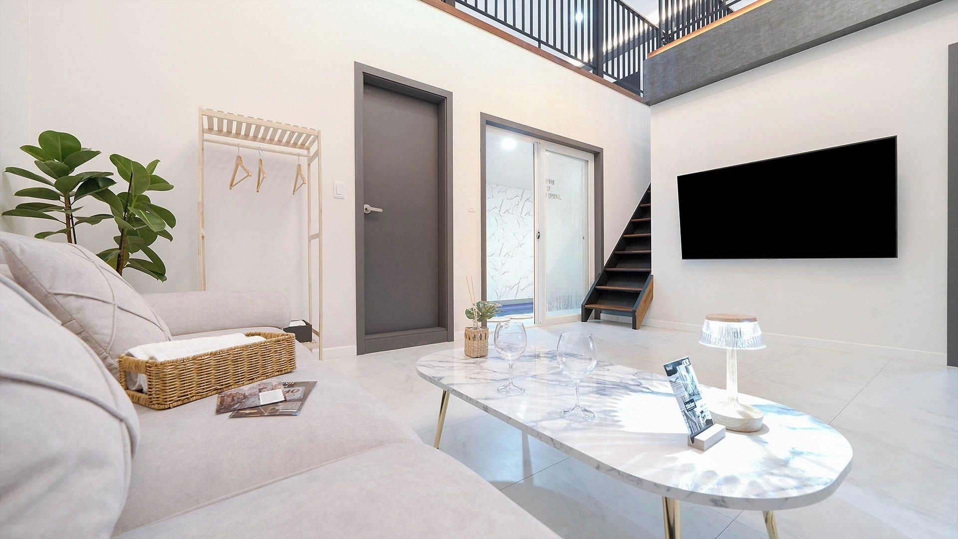 A modern living room with a sofa, a coffee table, a TV, and a staircase.