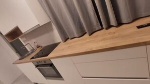Eine moderne Küche mit einer Holzarbeitsplatte, einem eingebauten Backofen und grauen Vorhängen.