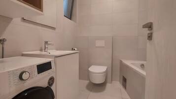 Un baño pequeño con inodoro, lavamanos y lavadora.