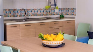 A modern kitchen with a wooden table, light-colored chairs, and a bowl of lemons on the table. - Apartment B6 third row first floor (Fondo Morte)