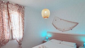 A neatly made bed with towels, a bedside lamp, and a hanging light fixture. - Apartment B6 third row first floor (Fondo Morte)