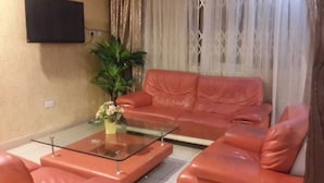 Un salon avec un canapé en cuir rouge, une table basse en verre et une plante en pot.
