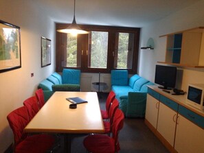 Cozy room with a dining table, sofa, and TV, perfect for relaxing.