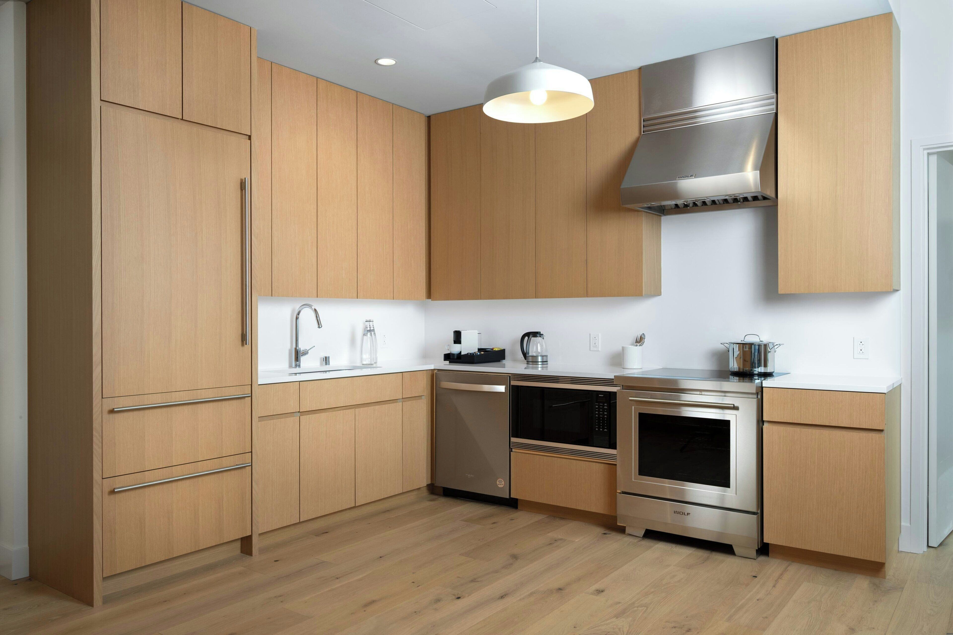 A modern kitchen with wooden cabinets, stainless steel appliances, and a pendant light.