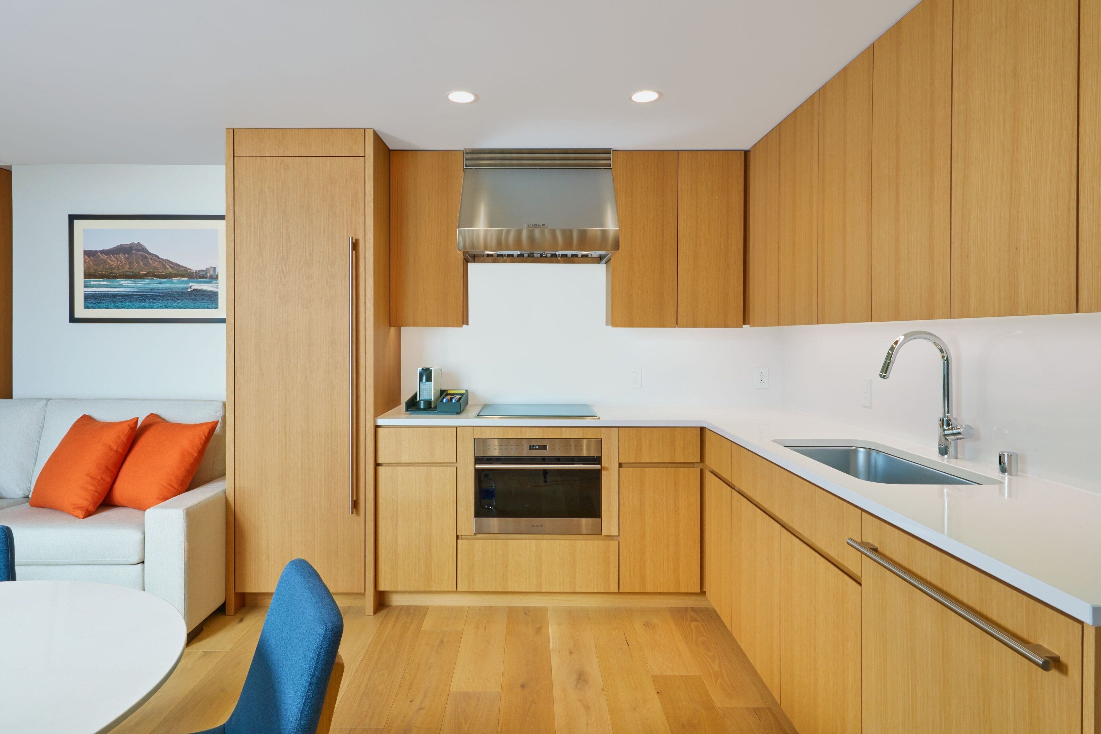 A modern kitchen with wooden cabinets, a stainless steel range hood, and a built-in oven.