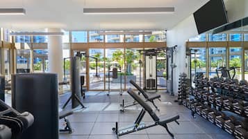 Et fitnesscenter med forskellig træningsudstyr, store vinduer og udsigt udad.