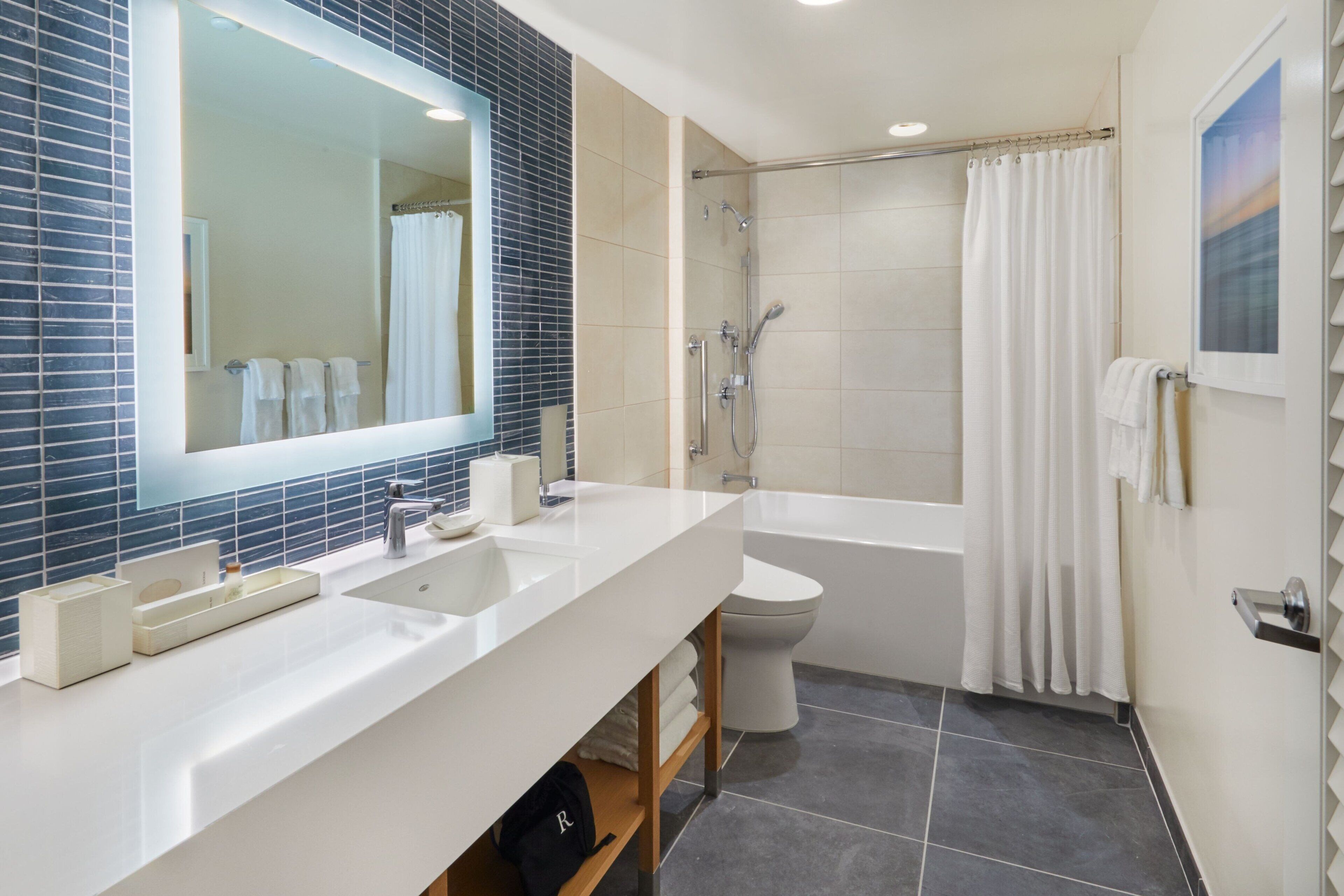 A modern bathroom with a white sink, mirror, and bathtub.