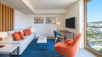 Een moderne hotelkamer met een bank, fauteuil, salontafel en een televisie.