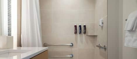 A modern bathroom with a bathtub, a vanity with a mirror, and a towel rack.