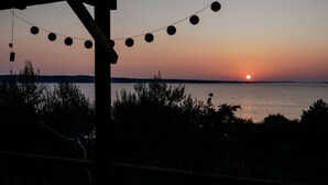 Een uitzicht op de ondergaande zon vanaf een overdekt terras met lichtjes.