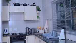 A modern kitchen with white cabinets, a stove, oven, and a window with blinds.