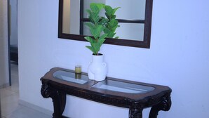 A bathroom with a mirror, a potted plant, and a glass-top vanity.