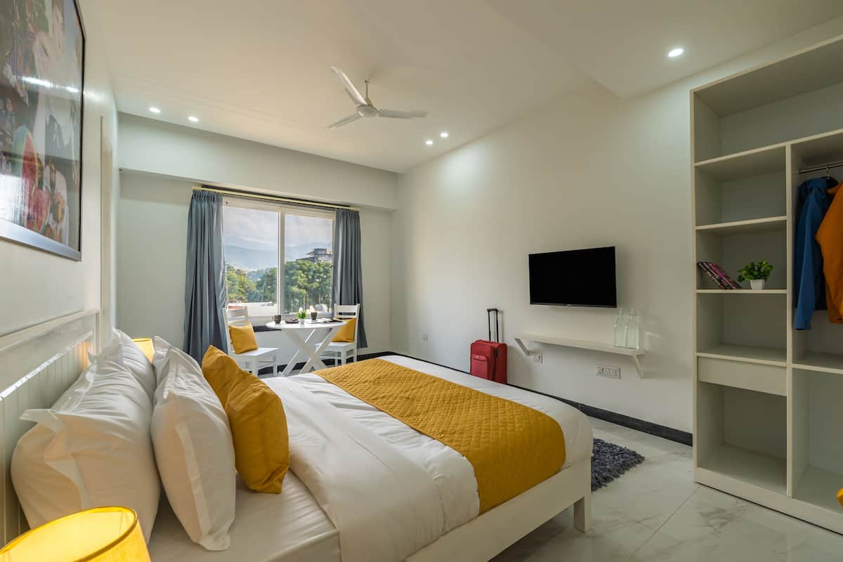 Ein Hotelzimmer mit Bett, Fernseher, Kleiderschrank und Fenster mit Blick ins Freie.