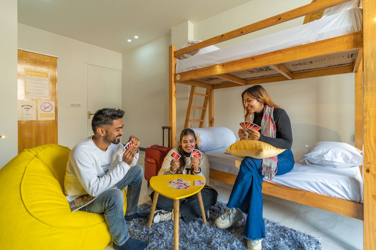 Ein Zimmer mit Etagenbetten, einem gelben Sitzsack, einem kleinen Tisch und einem roten Koffer.