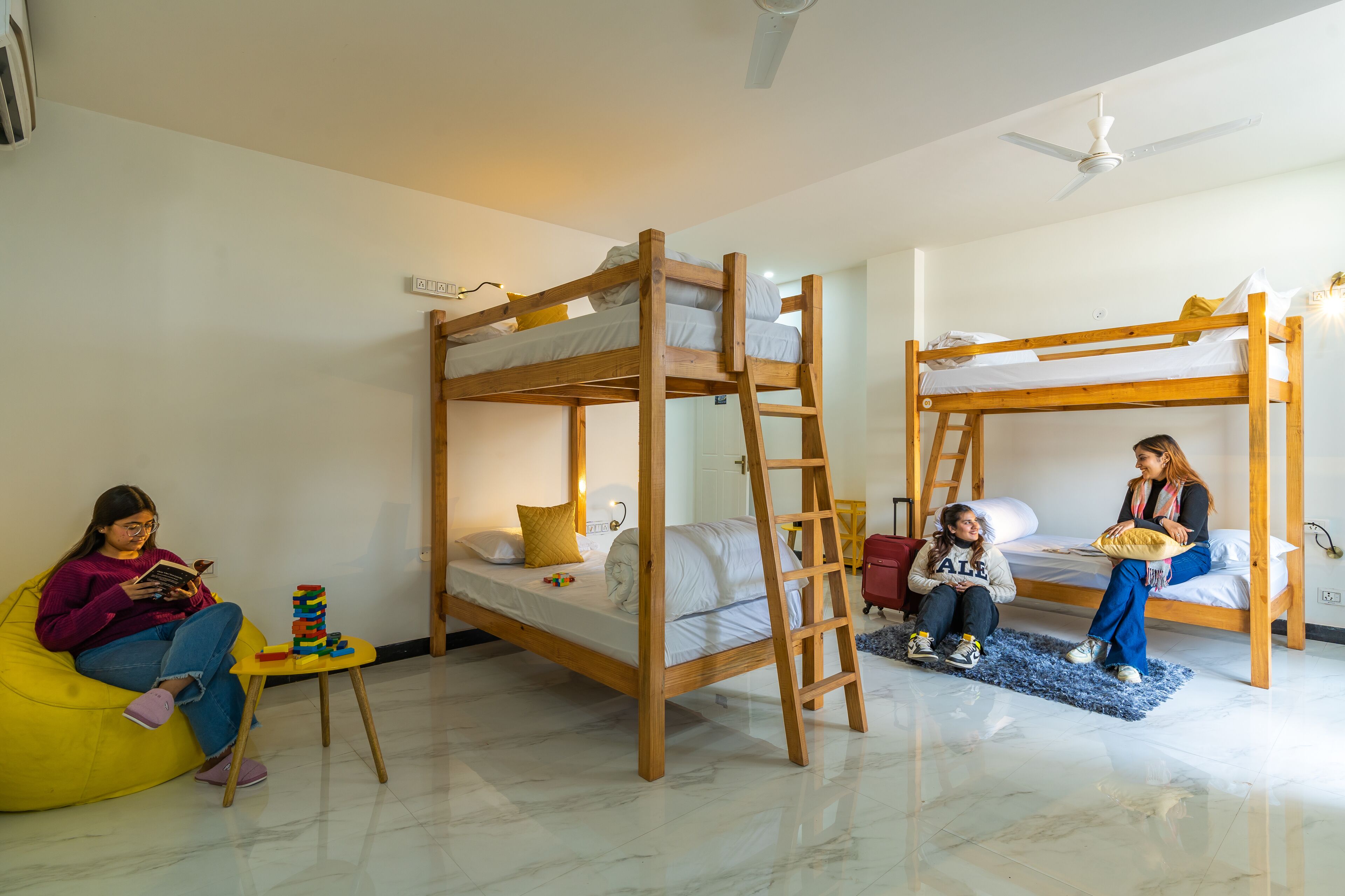 A room with two bunk beds, a small table with toys, and a yellow bean bag chair.