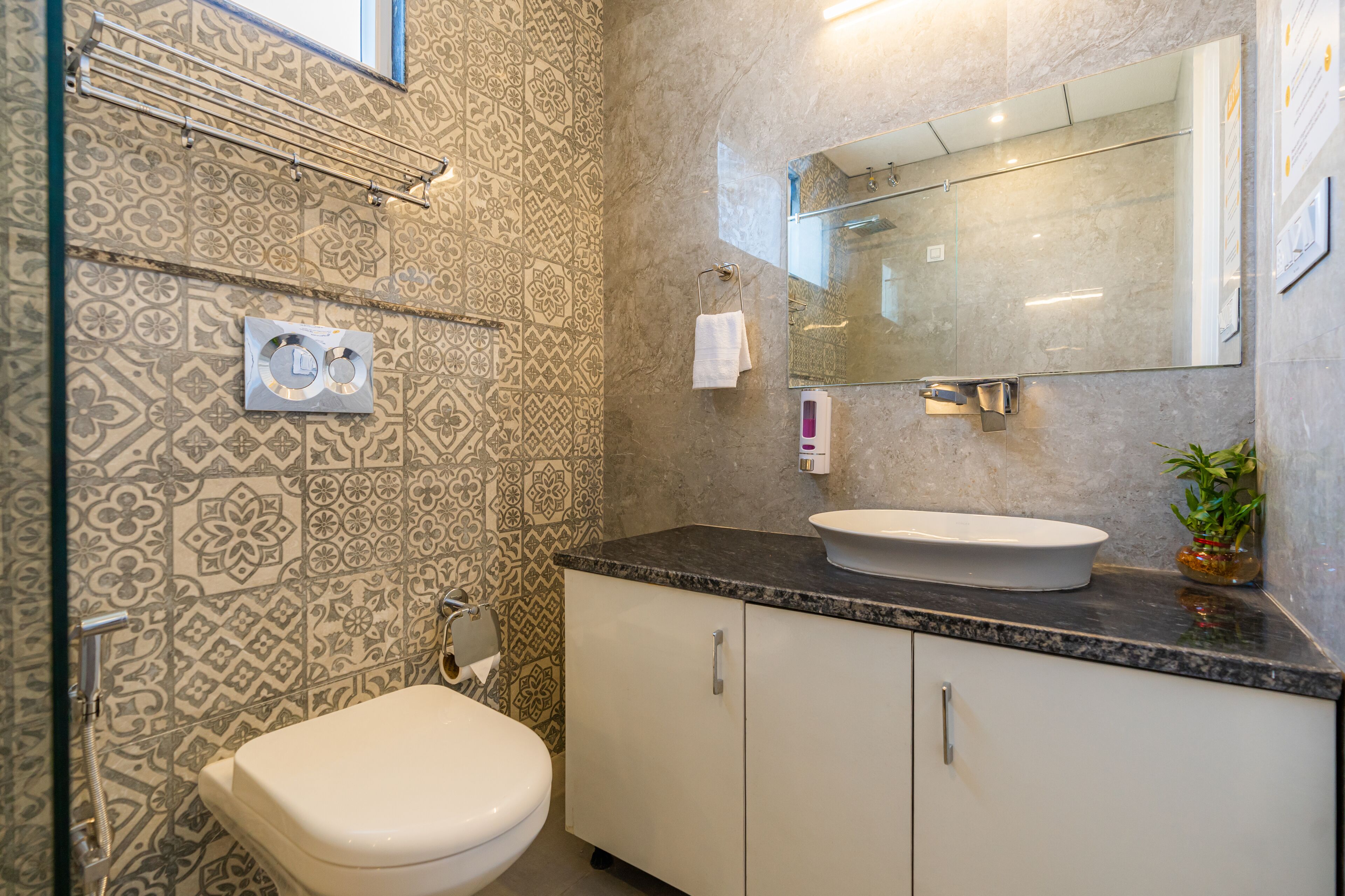 A bathroom with patterned tiles, a toilet, a sink with a mirror, and a cabinet.