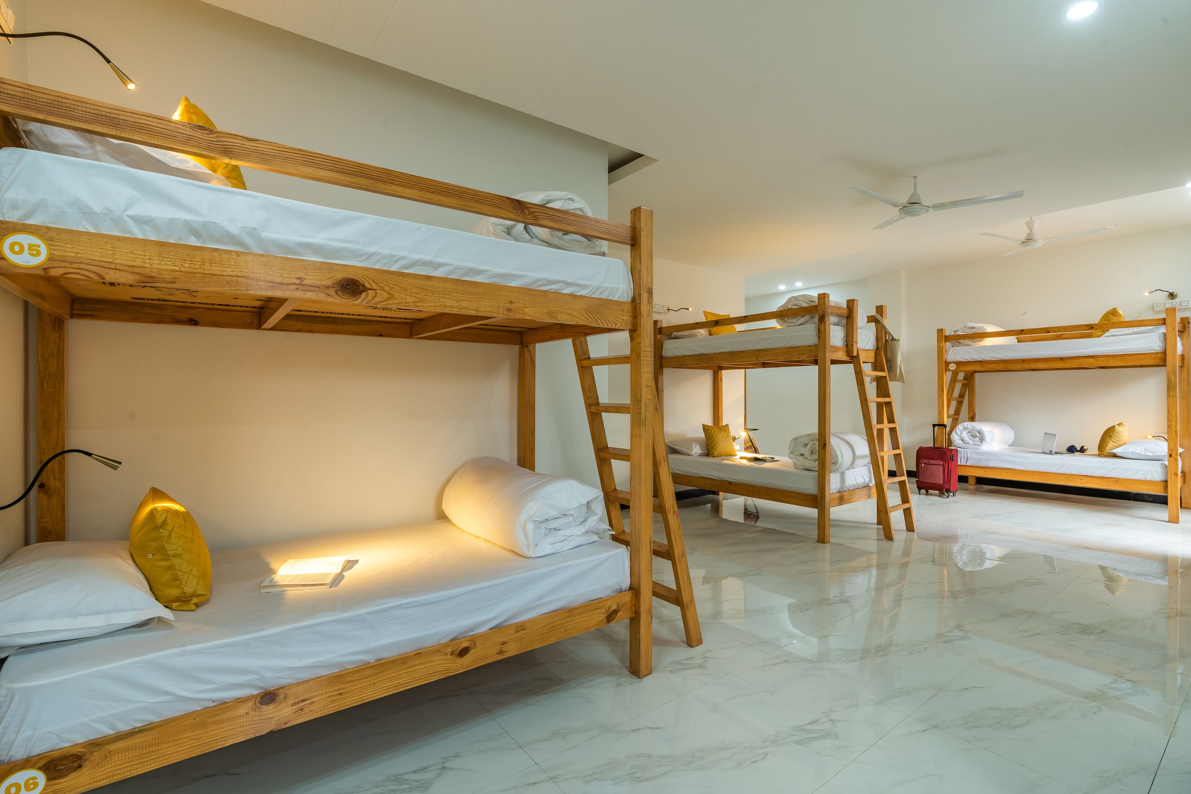 Habitación con literas de madera, ropa de cama blanca y un escritorio pequeño con lámpara.