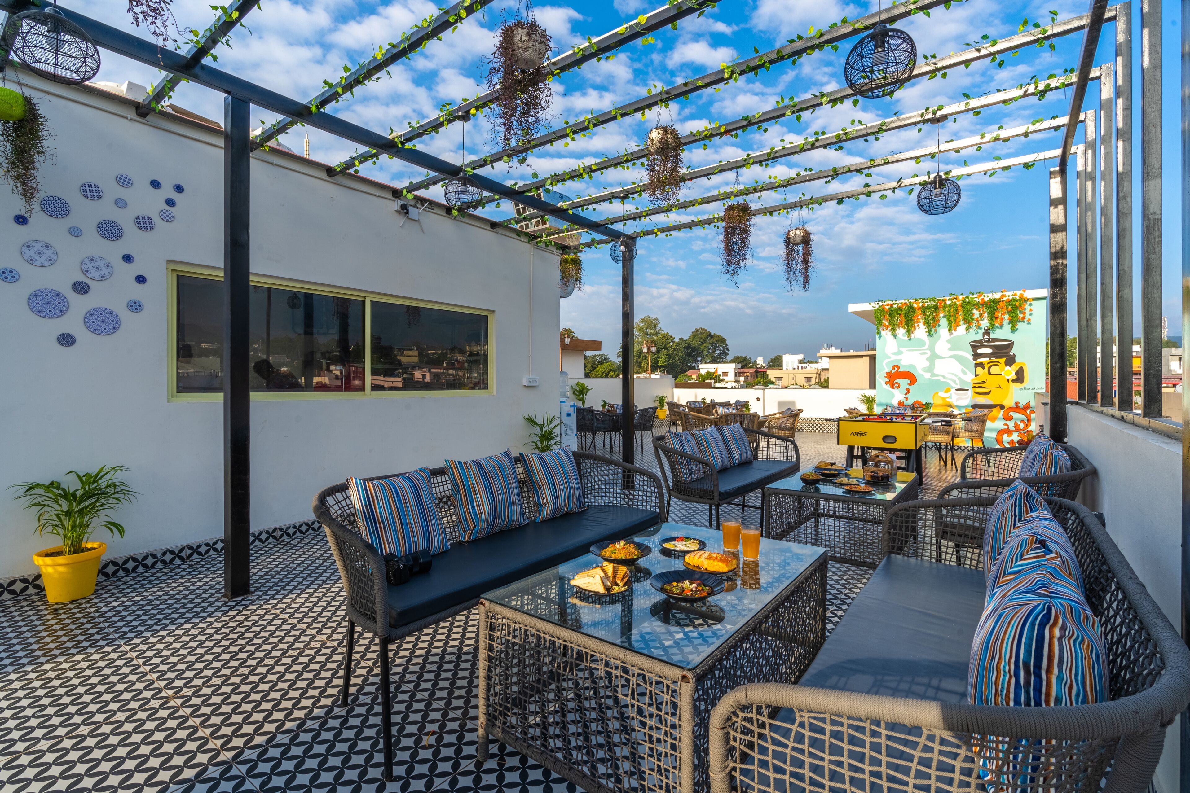 An outdoor patio with a patterned floor, seating area, and hanging plants.