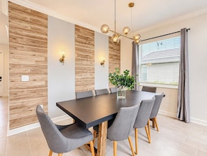 A dining area with a long table, six chairs, a vase with greenery, and a modern chandelier. - Sunny Escape/ Private Pool, Jacuzzi & Waterpark (Davenport)
