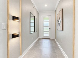A hallway with a door, framed artwork, and recessed lighting.