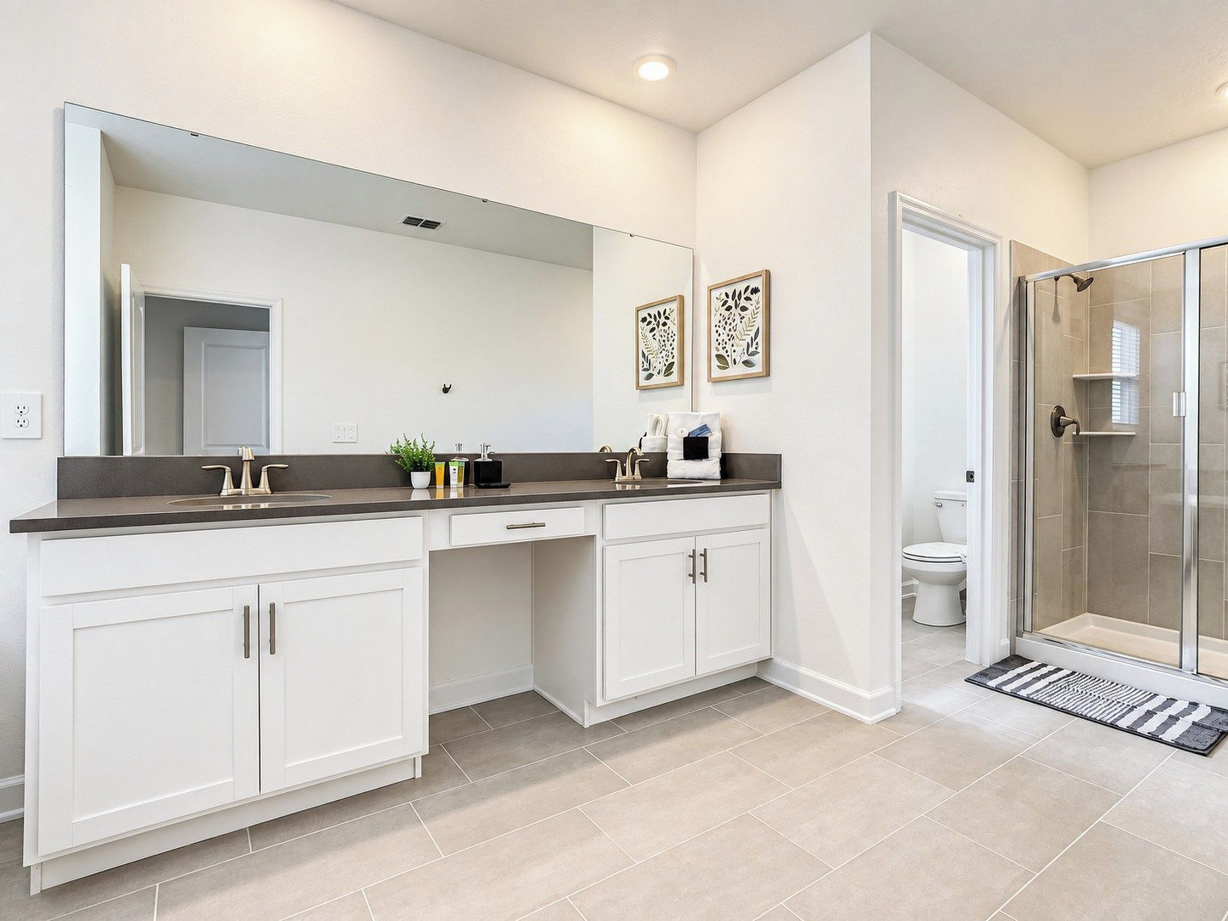 A modern bathroom with a large mirror, a shower enclosure, and a toilet.