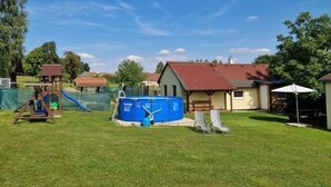 Takapihalla on uima-allas, liukumäki ja pieni puinen leikkimökki.