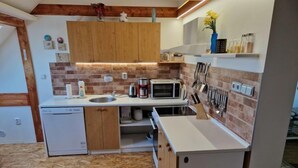 Pieni, käytännöllinen keittiö, jossa on puukehikoiset kaapit, mikroaaltouuni, kahvinkeitin ja pesuallas.