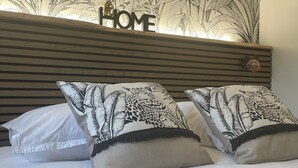 A bed with white bedding and two decorative pillows with a leaf pattern.