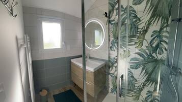 Une salle de bain moderne avec une douche à l’italienne en verre, un lavabo avec un miroir et une fenêtre.