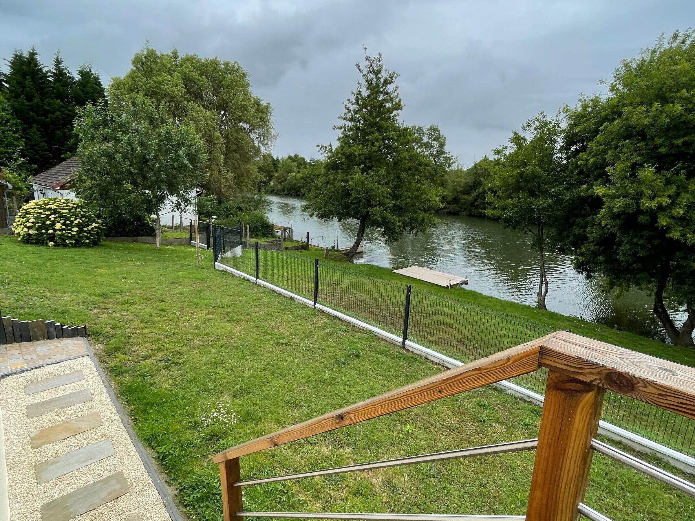 A grassy area with a wooden deck and a river view.