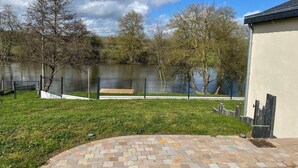 A landscaped outdoor area with a paved walkway, a fenced pond, and trees.