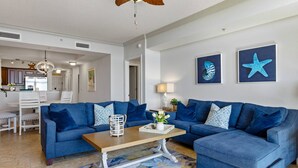 A living room with two blue sofas, a wooden coffee table, and a ceiling fan.