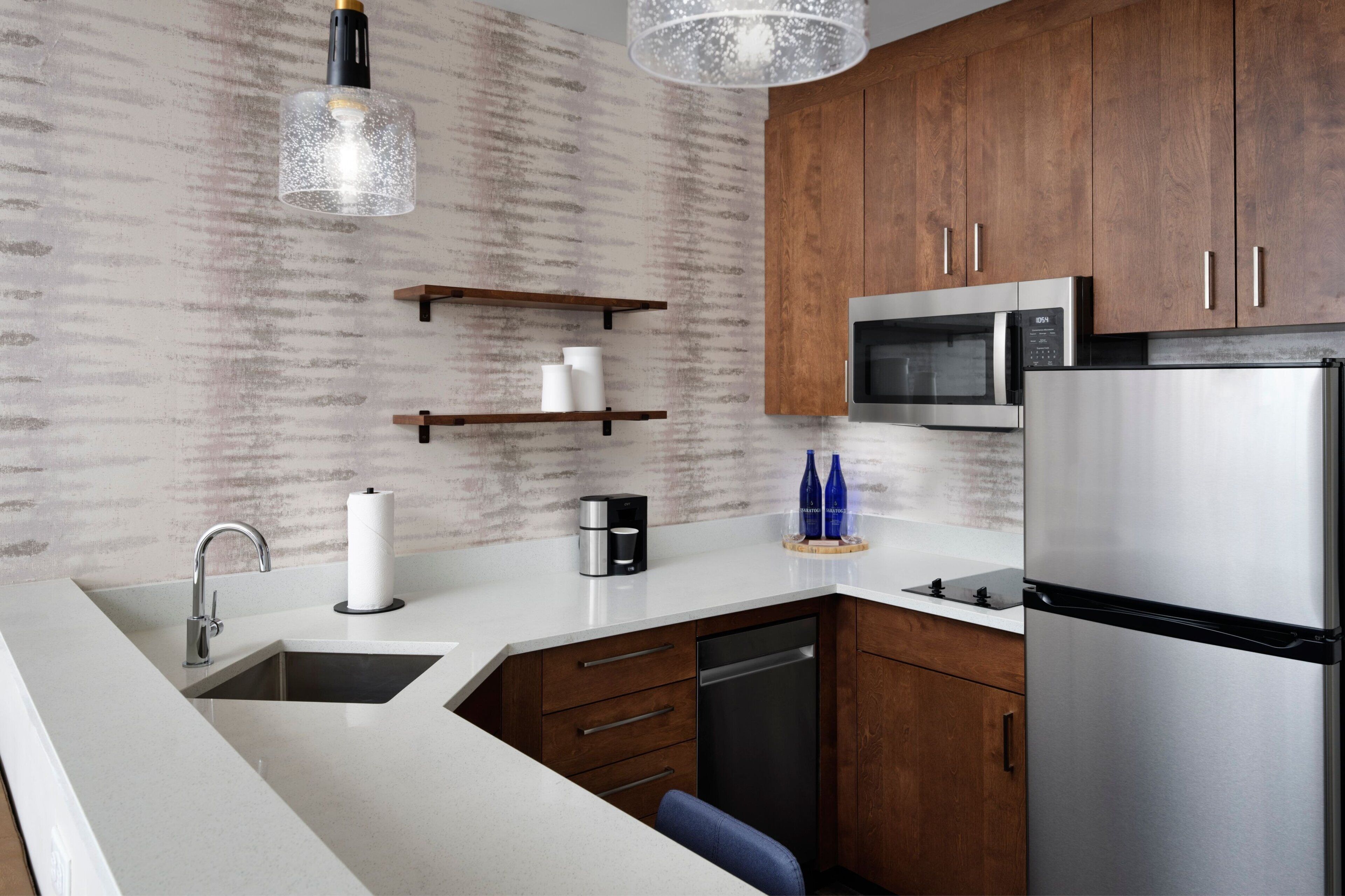A modern kitchen with wooden cabinets, stainless steel appliances, and a white countertop.