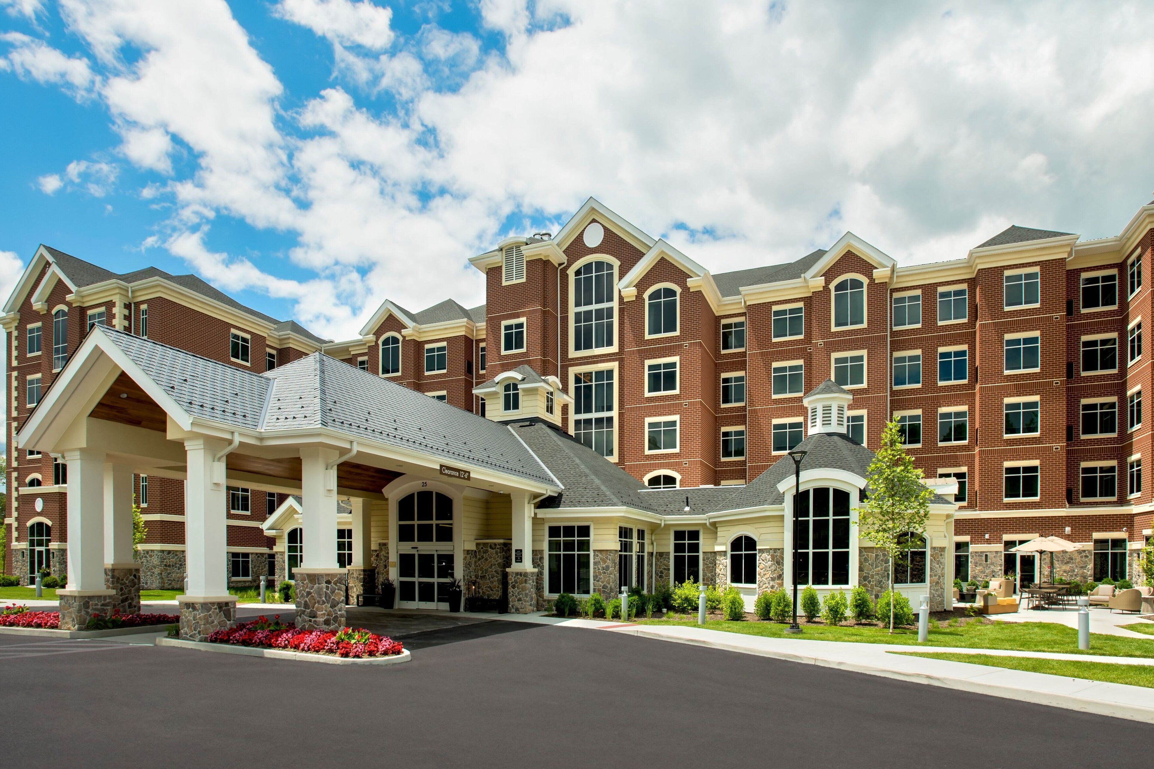 A multi-story hotel with a brick facade, large windows, and a covered entrance area with a stone base.