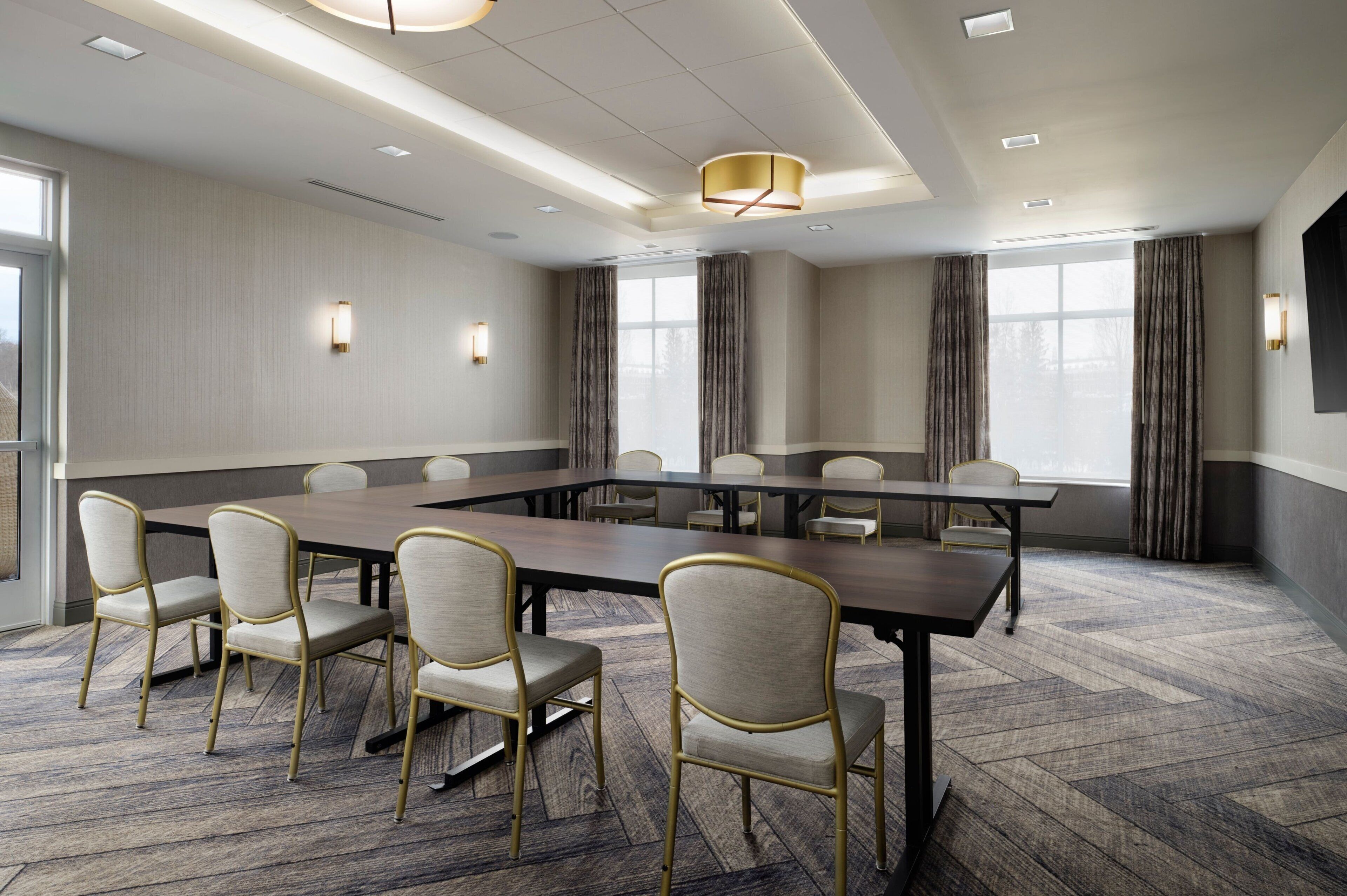 A conference room with a long table, several chairs, and a modern chandelier.