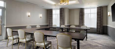 A conference room with a long table, several chairs, and a modern chandelier.