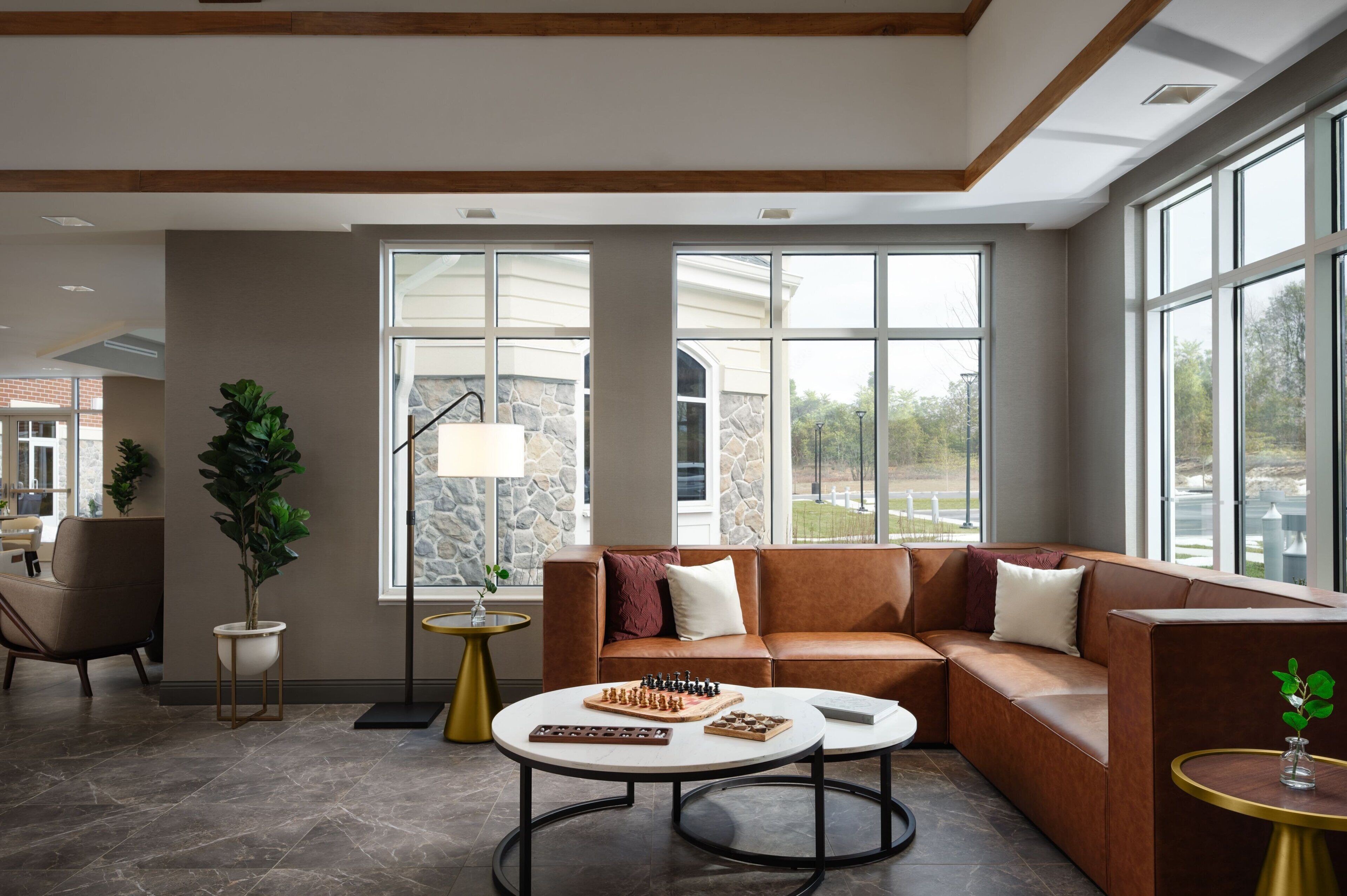 A modern living room with a leather sofa, two round coffee tables, and a chessboard.