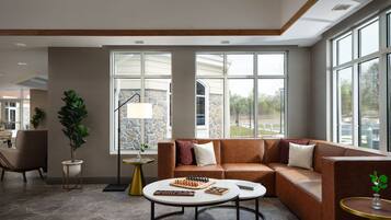 A modern living room with a leather sofa, two round coffee tables, and a chessboard.