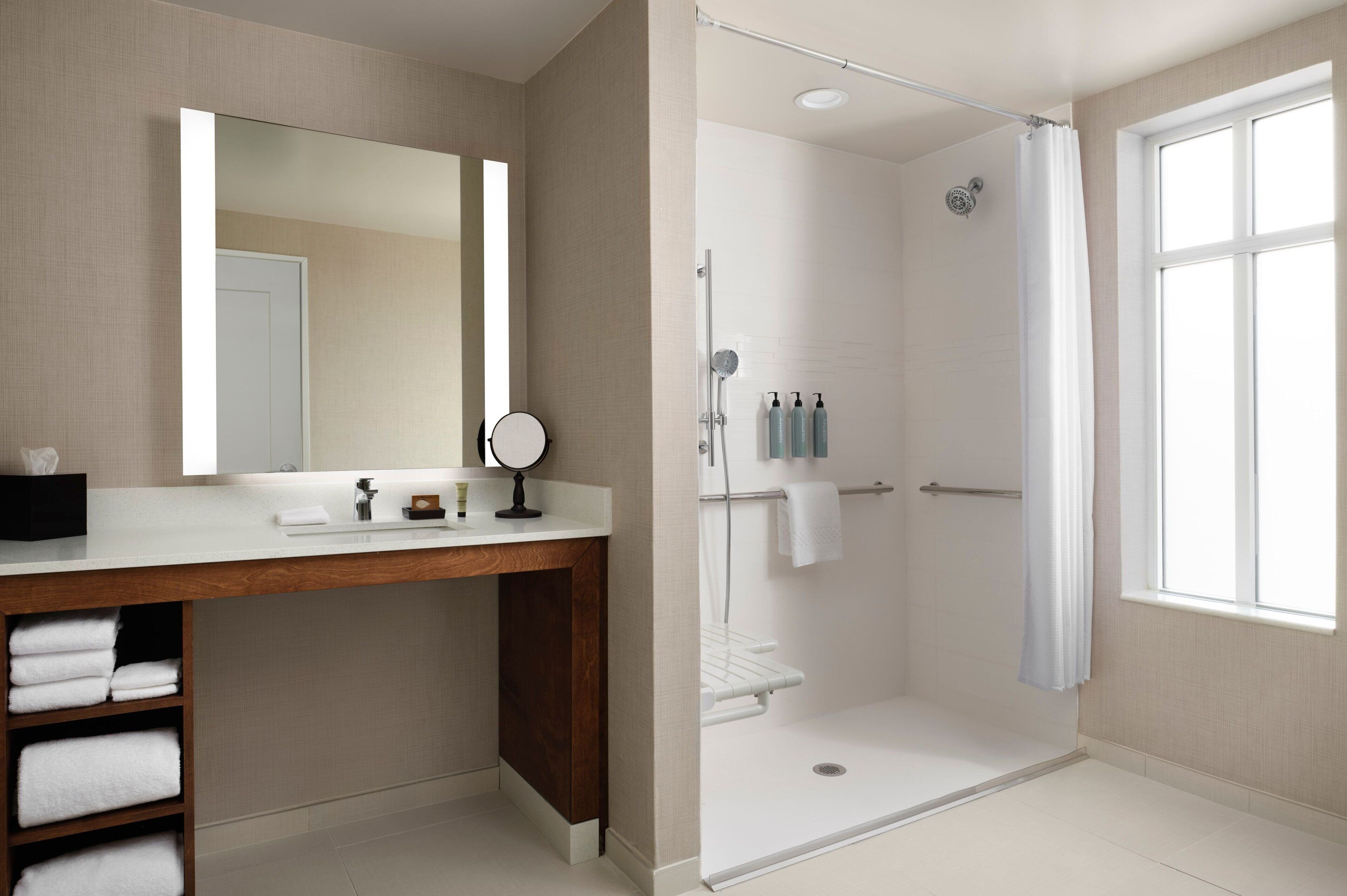 A modern bathroom with a shower, a vanity with a mirror, and a window.