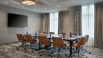 Une salle de conférence avec une grande table, des chaises marron et des bouteilles d’eau bleues.