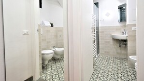Et badeværelse med brusebad, toilet, bidet og vask.