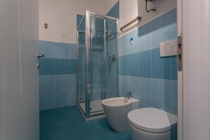 Une salle de bain avec une douche à parois de verre, un lavabo blanc et des toilettes.
