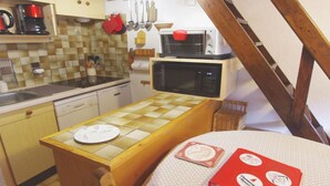 Cocina compacta equipada con microondas, cafetera y utensilios colgantes.